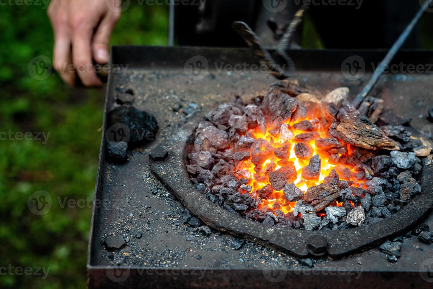 Herrero forjando una tira de metal caliente foto