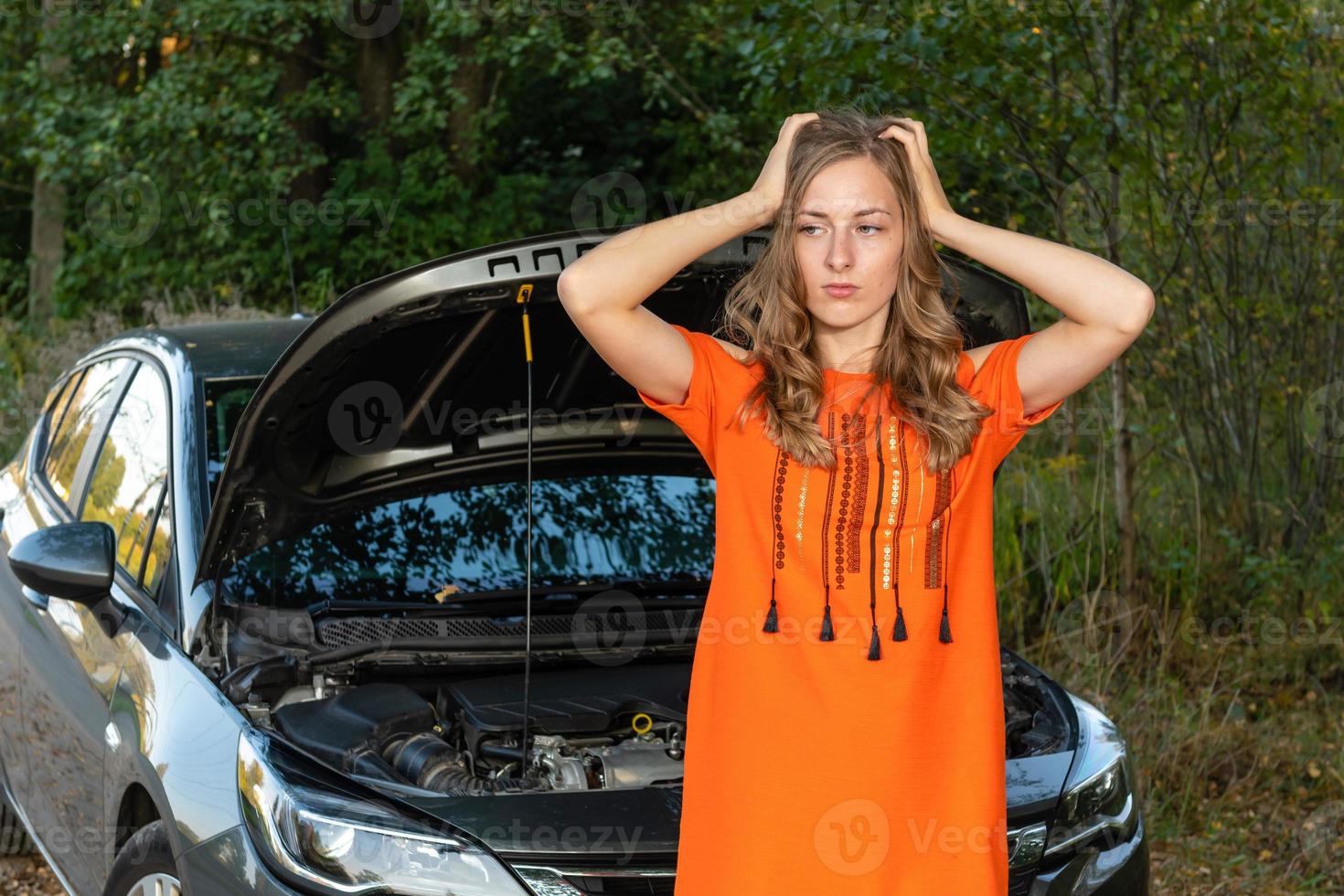 Pretty, young woman by the roadside after her car has broken down photo