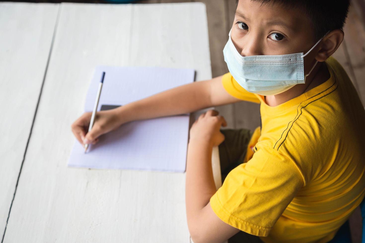 concepto de educación, escuela y pandemia - niño estudiante con máscara médica protectora facial para protegerse de enfermedades virales foto