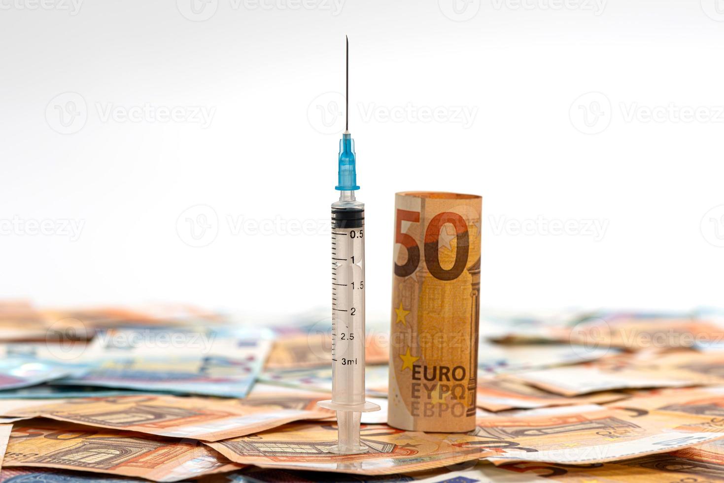 Billetes en euros con jeringa encima de ellos foto