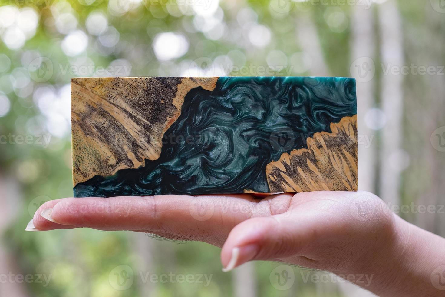Hand holding epoxy resin Stabilizing Afzelia burl exotic wood red lava background photo