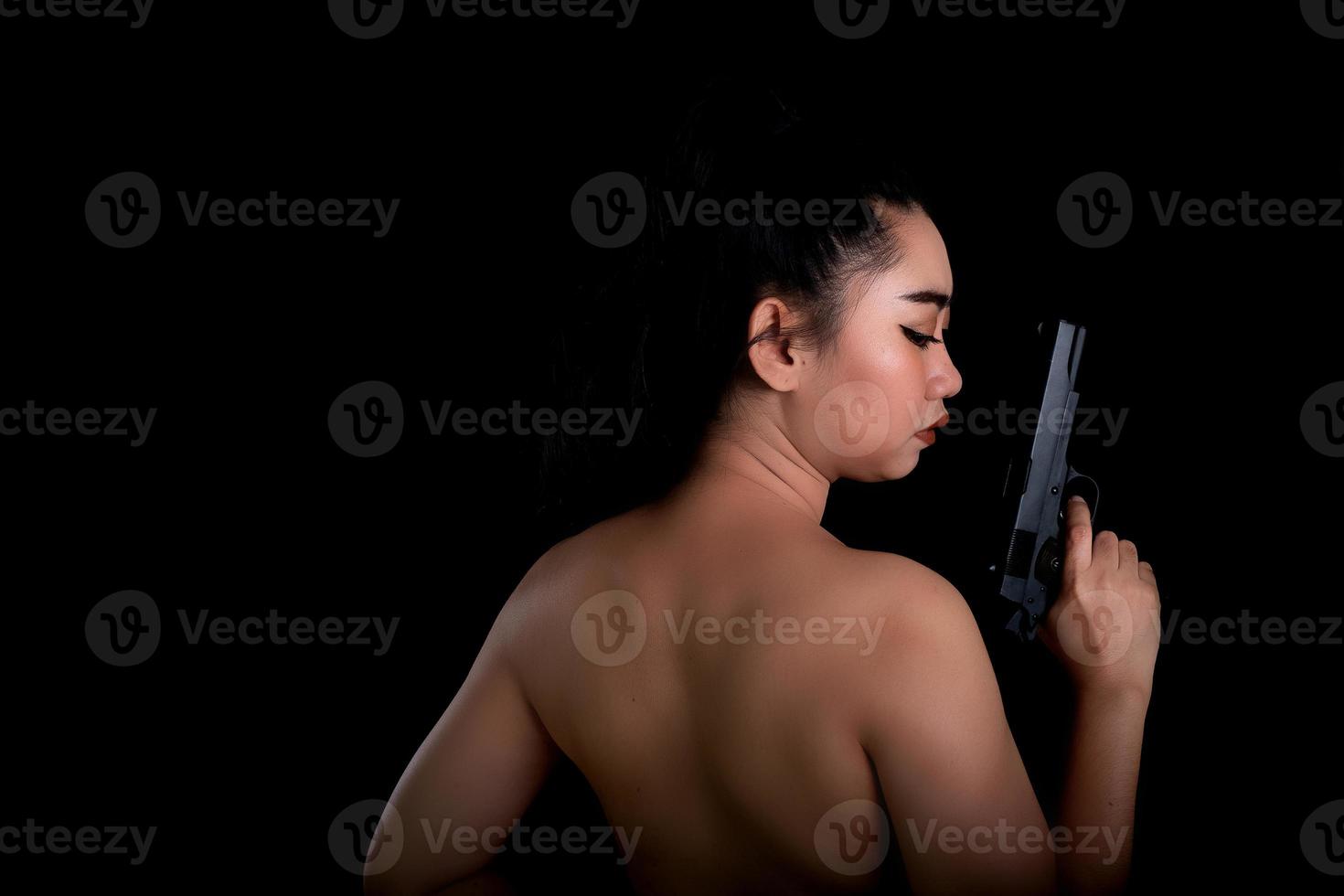 Asea woman wearing a yellow suit one hand holding a pistol gun at black background photo