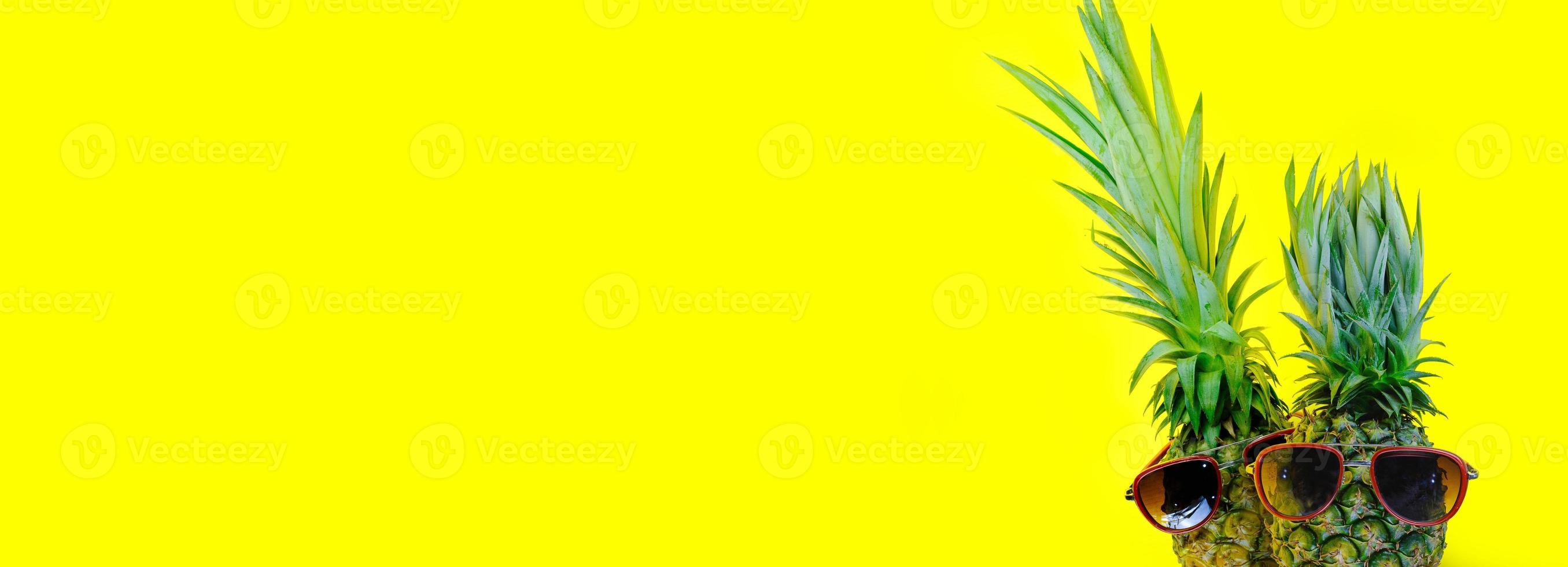 Piña con gafas de sol rojas sobre fondo amarillo aislado foto