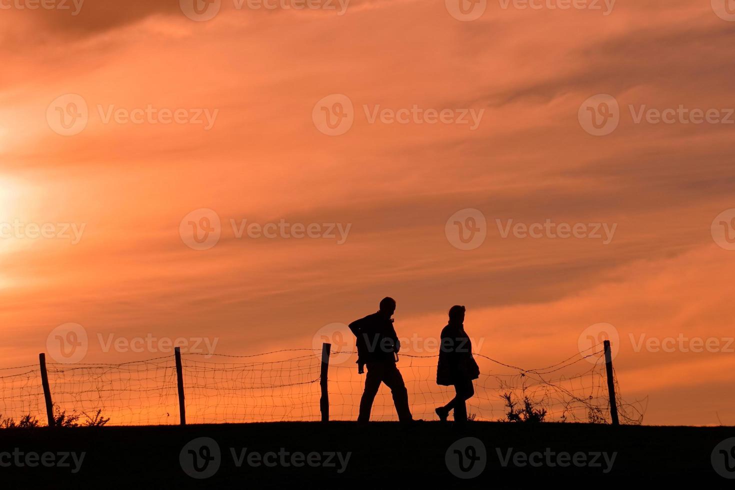 silhouette of a couple trekking in the mountian with a sunset photo