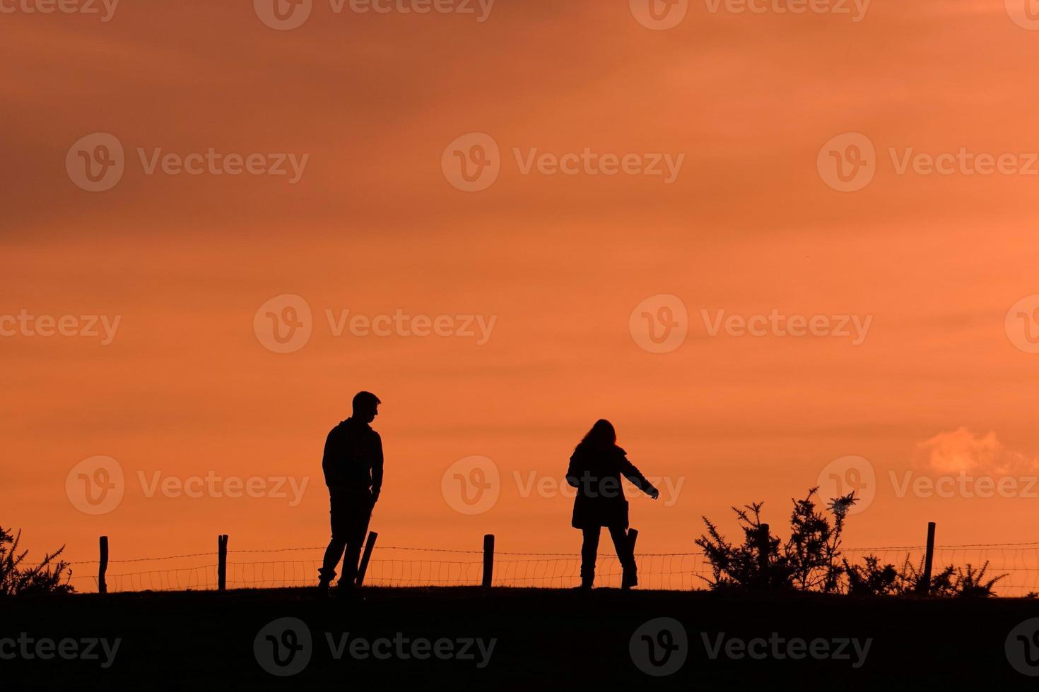 silhouette of a couple trekking in the mountian with a sunset photo