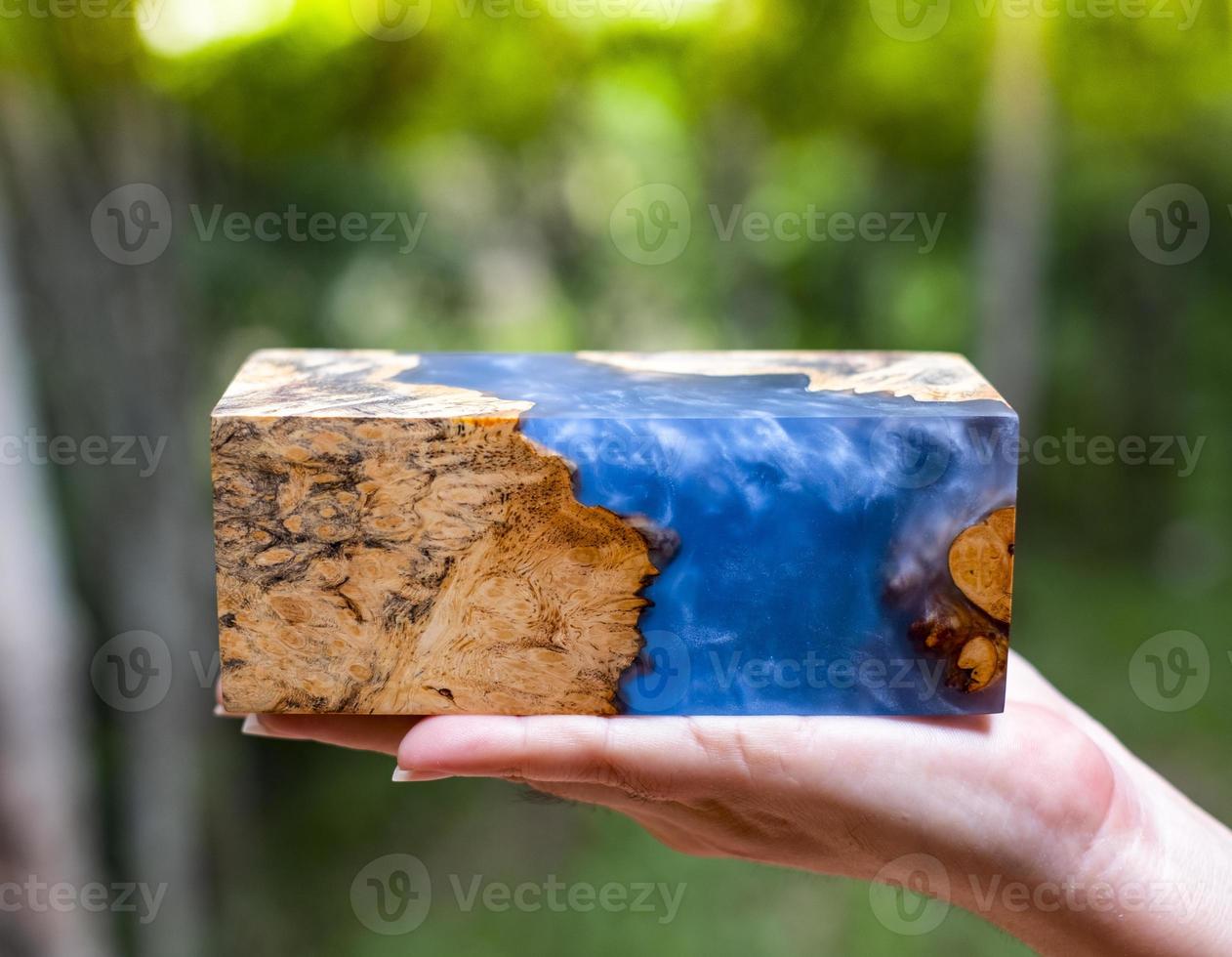 Mano sujetando resina epoxi estabilizadora afzelia burl madera exótica fondo de lava roja foto