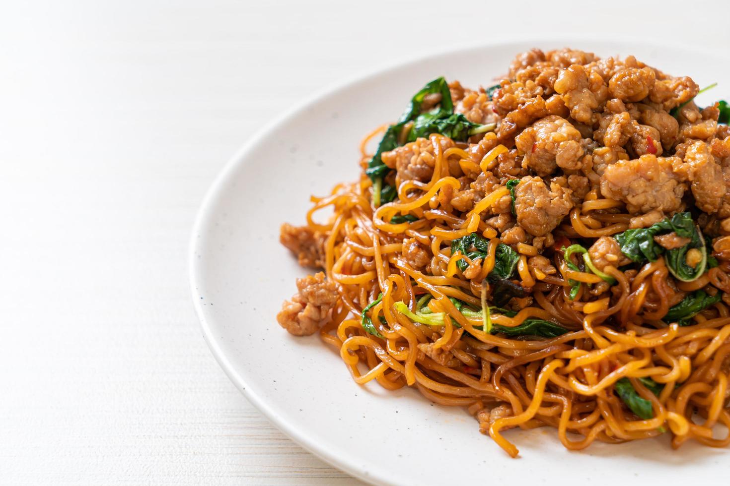 fideos instantáneos salteados con albahaca tailandesa y carne de cerdo picada - estilo de comida asiática foto