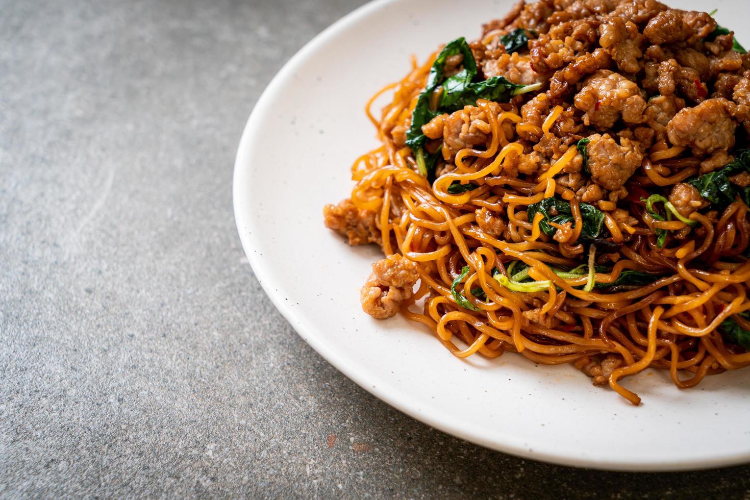 fideos instantáneos salteados con albahaca tailandesa y carne de cerdo picada - estilo de comida asiática foto