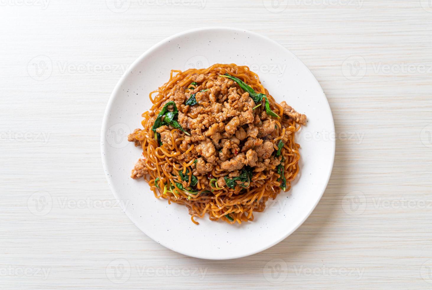 fideos instantáneos salteados con albahaca tailandesa y carne de cerdo picada - estilo de comida asiática foto