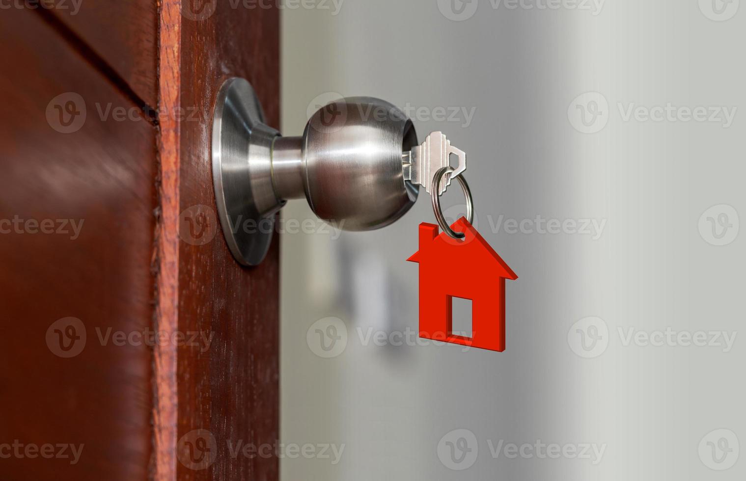 Puerta abierta con llaves, llave de la casa en el ojo de la cerradura con casa pequeña foto