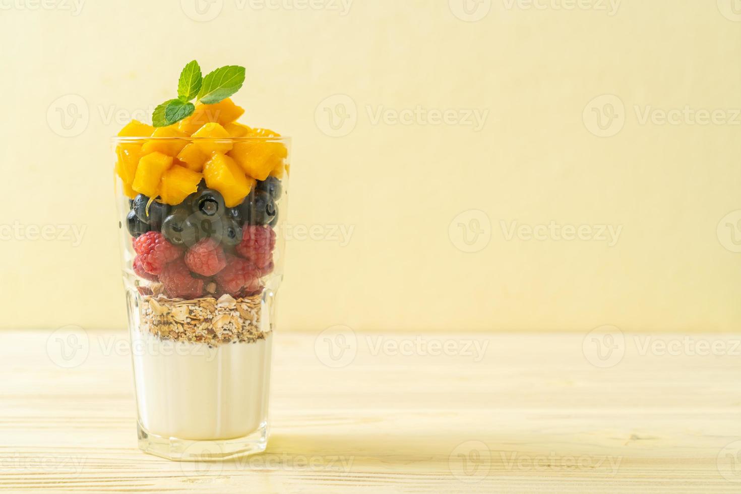 mango, frambuesa y arándano caseros con yogur y granola - estilo de comida saludable foto