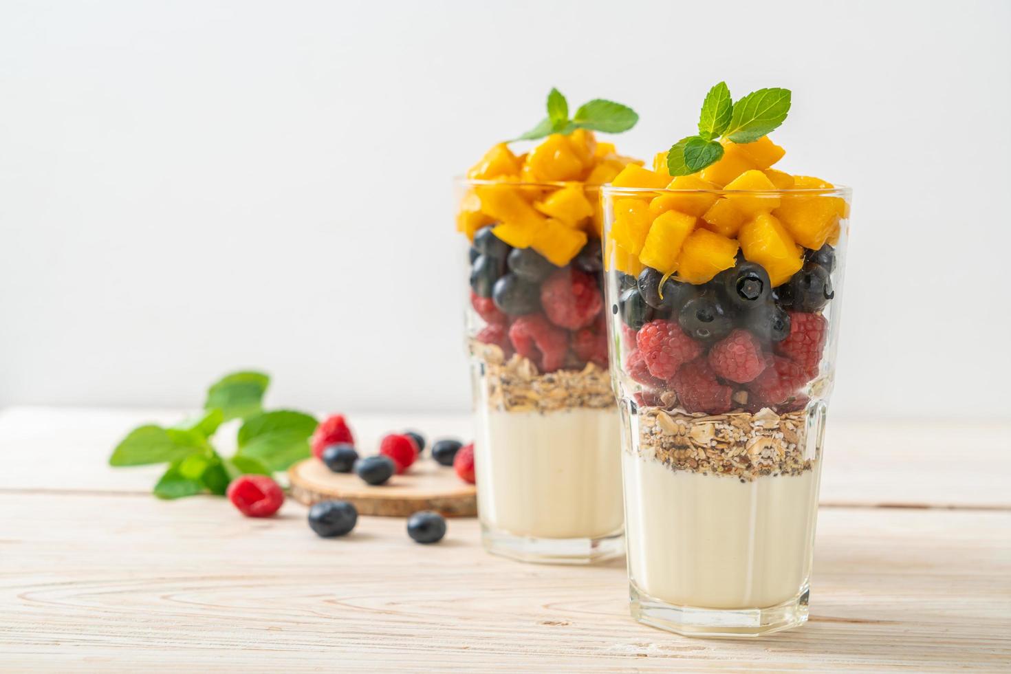 mango, frambuesa y arándano caseros con yogur y granola - estilo de comida saludable foto