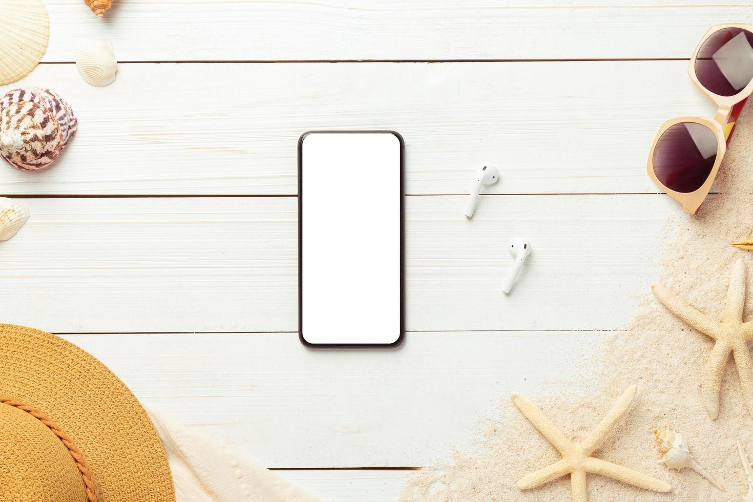 Summer background with blank screen phone and beach accessories on white wooden background top view with copy space. photo