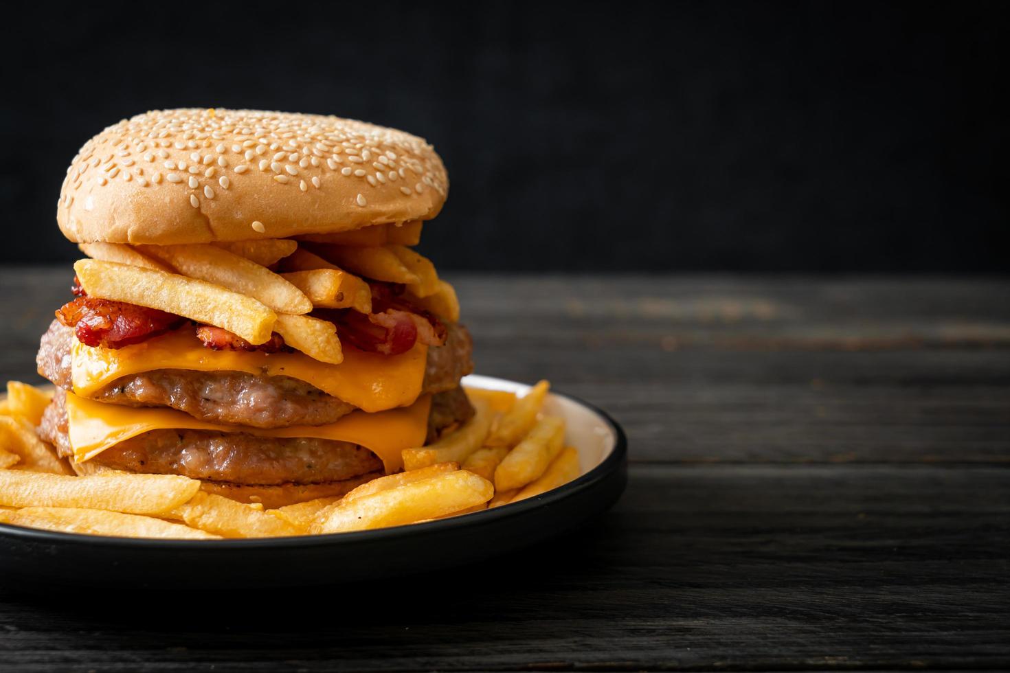 Pork hamburger or pork burger with cheese, bacon, and french fries photo