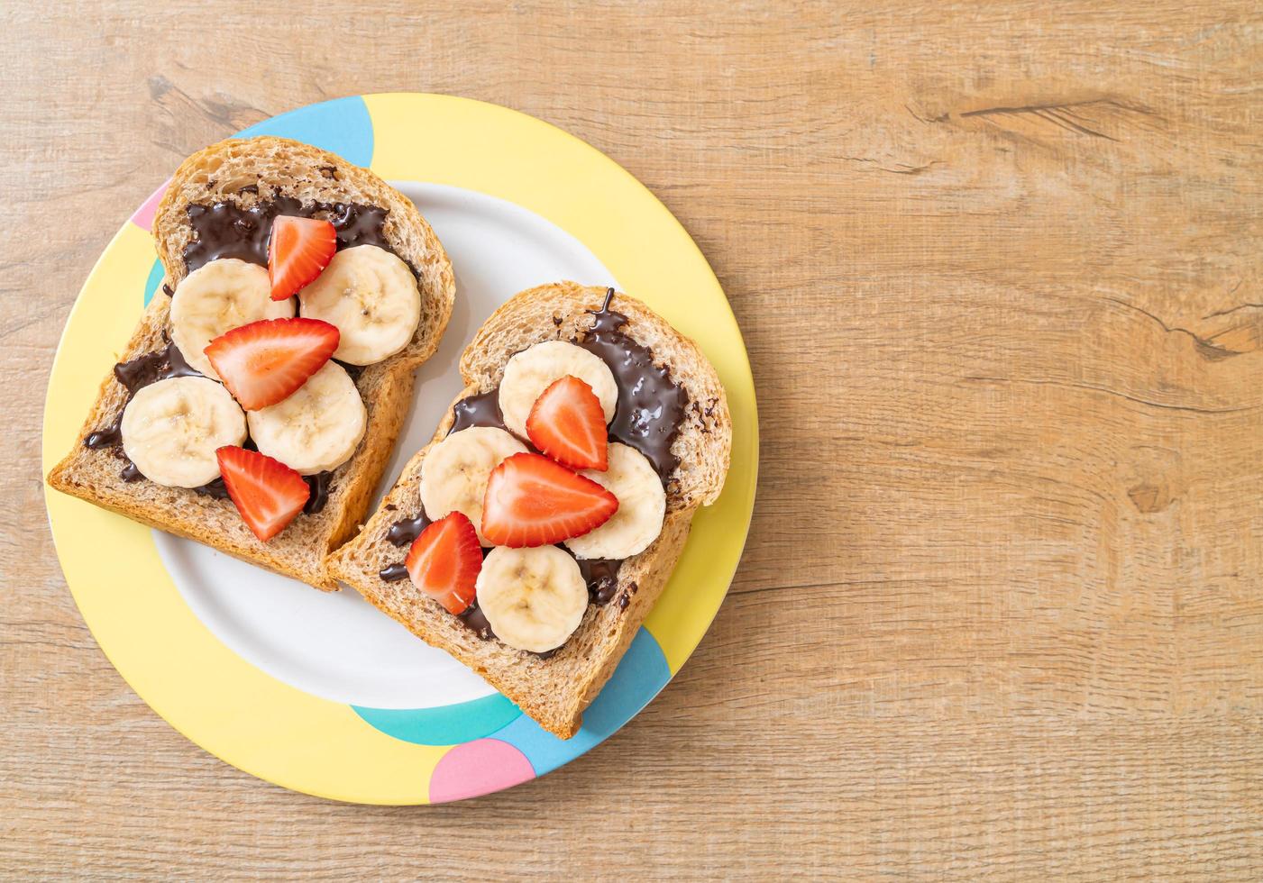 Whole wheat bread toasted with fresh banana, strawberry, and chocolate for breakfast photo