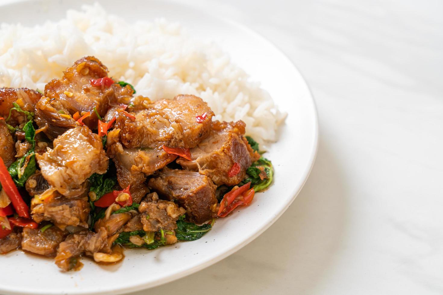 Panceta de cerdo crujiente salteada y albahaca con arroz - estilo de comida callejera local asiática foto