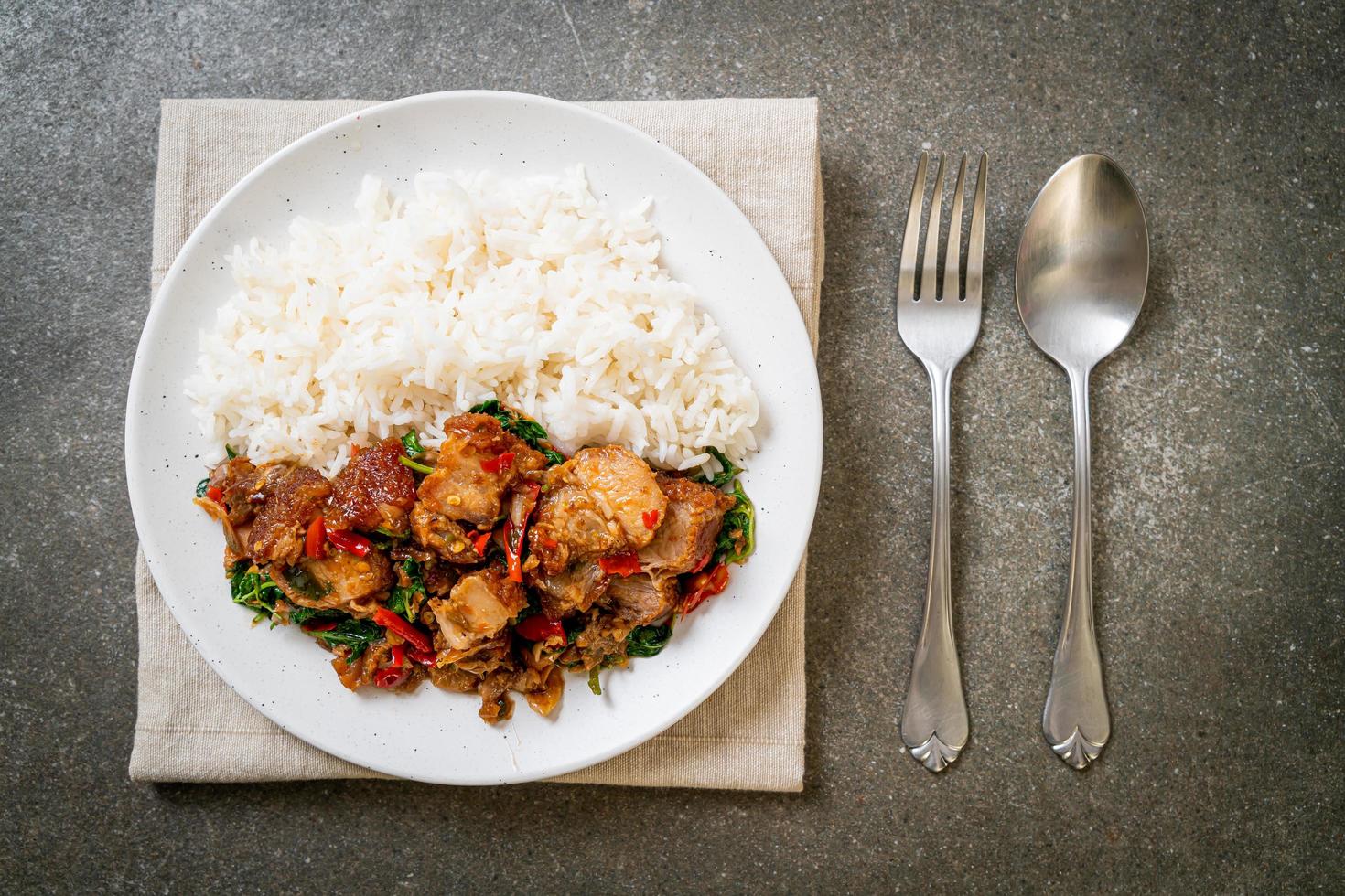 Panceta de cerdo crujiente salteada y albahaca con arroz - estilo de comida callejera local asiática foto