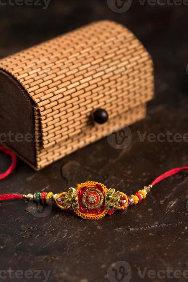 Raksha Bandhan background with an elegant Rakhi, Rice Grains, Kumkum and gift box. A traditional Indian wrist band which is a symbol of love between Brothers and Sisters. photo