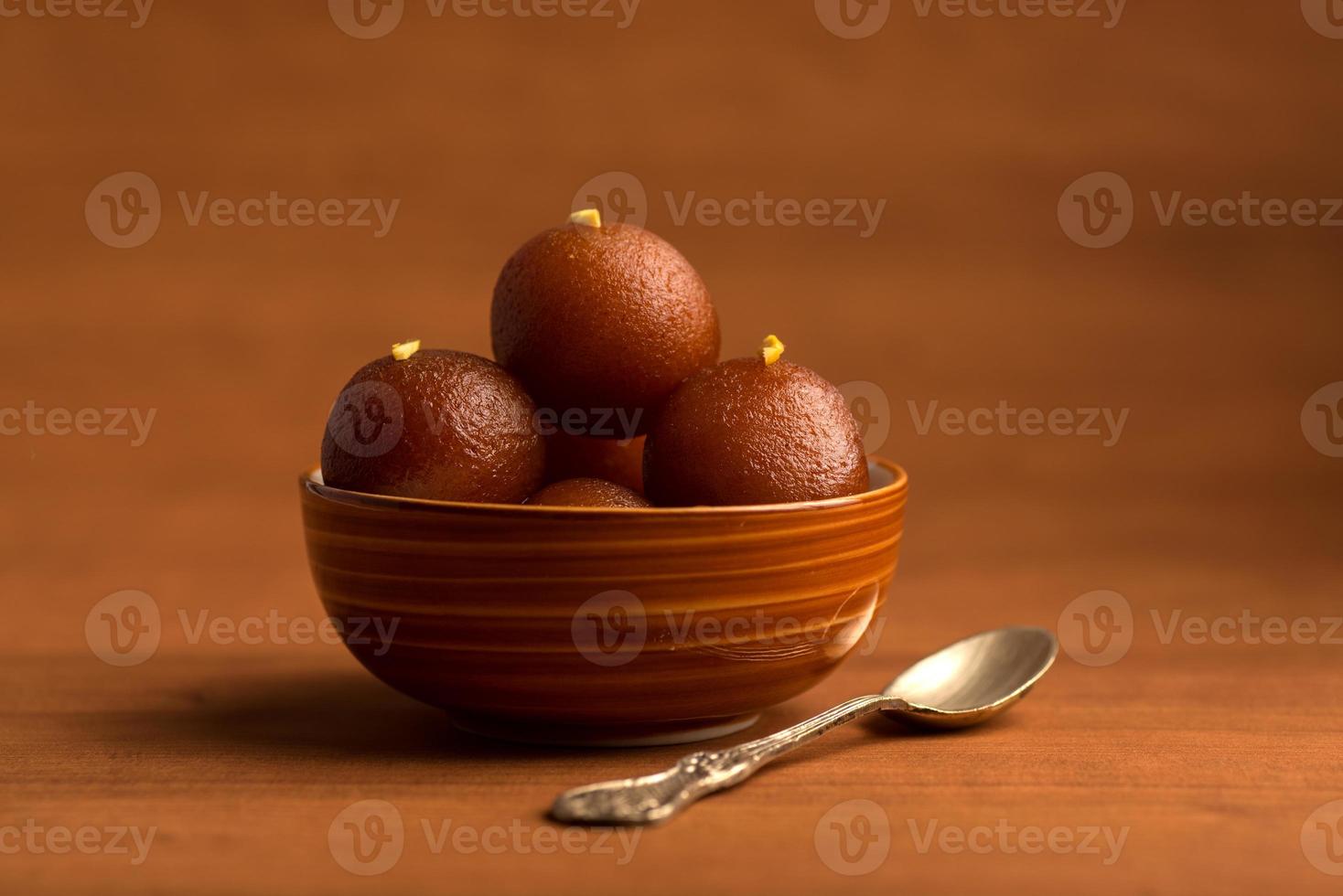 Gulab Jamun in bowl on wooden background. Indian Dessert or Sweet Dish. photo