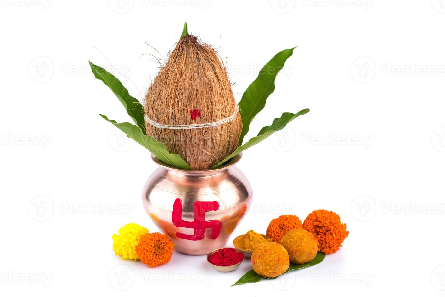 kalash de cobre con coco, hoja de mango, haldi, kumkum y dulces con decoración de flores de caléndula sobre un fondo blanco. esencial en puja hindú. foto