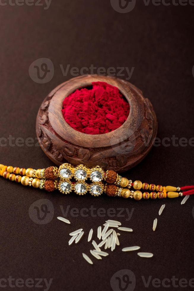 Raksha Bandhan background with an elegant Rakhi, Rice Grains and Kumkum. A traditional Indian wrist band which is a symbol of love between Brothers and Sisters. photo