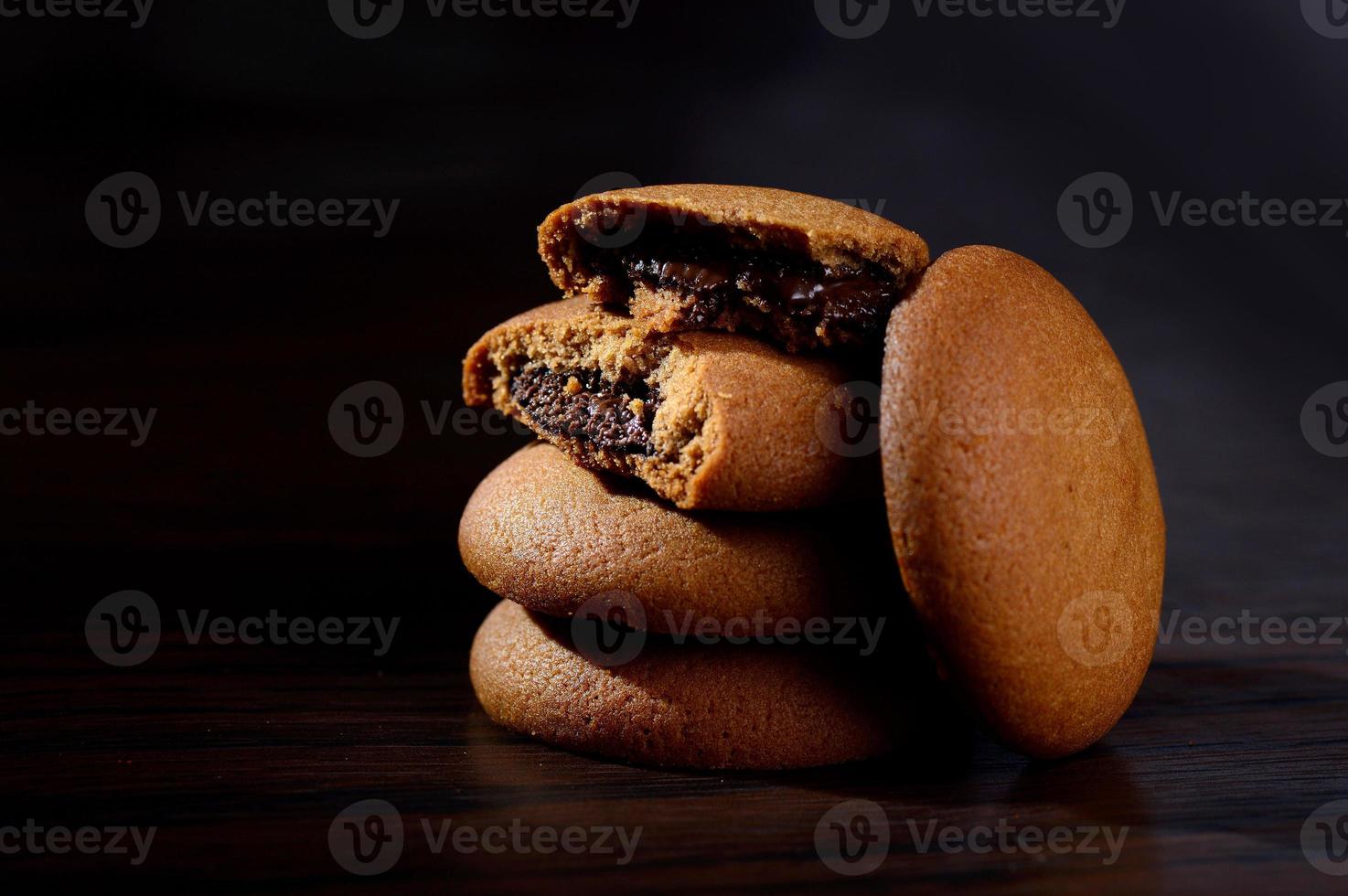 galletas rellenas de crema de chocolate. galletas de crema de chocolate. Galletas de chocolate marrón con relleno de crema sobre fondo negro. foto