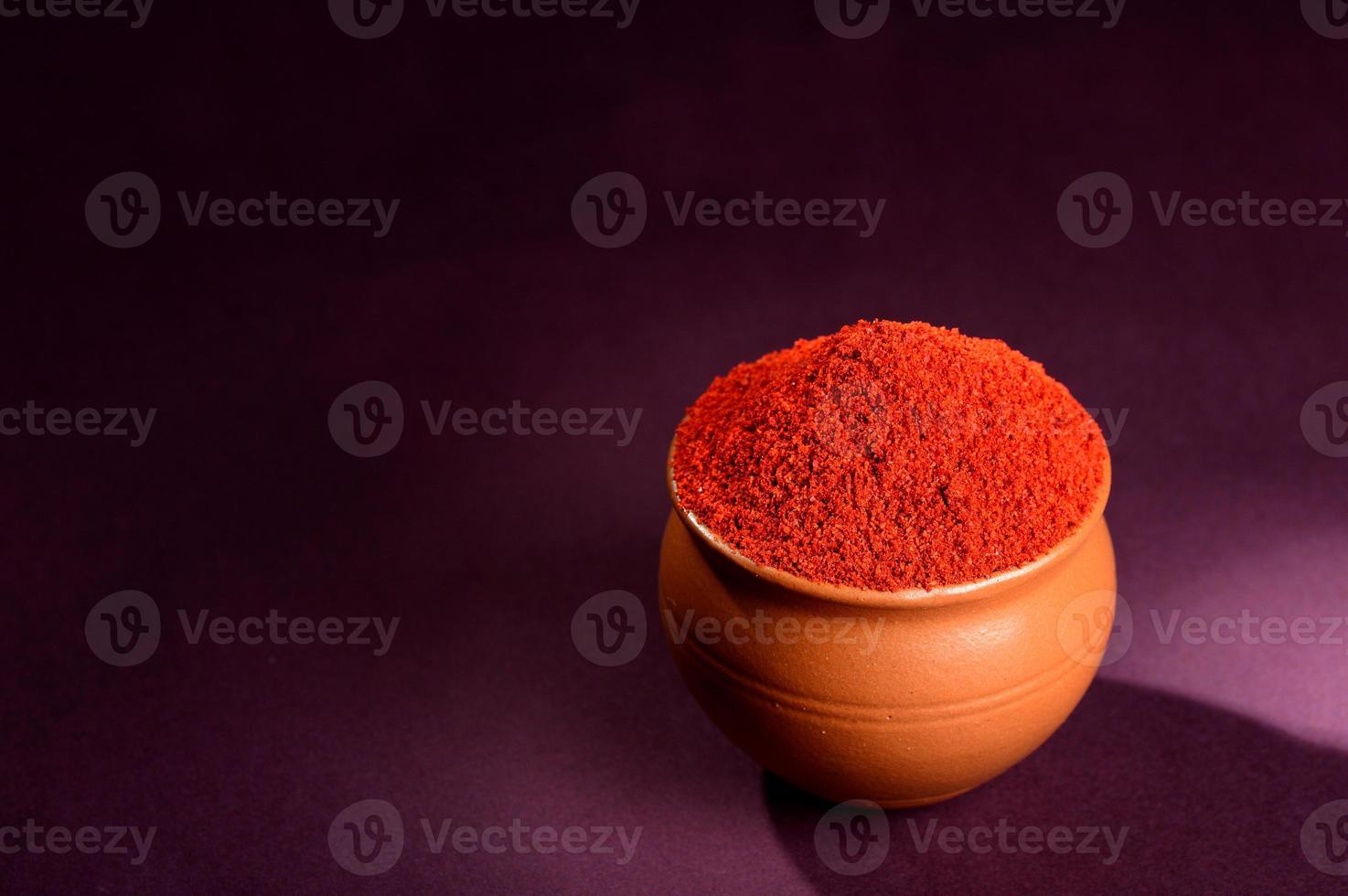 Ají rojo en polvo en una olla de barro sobre fondo oscuro foto