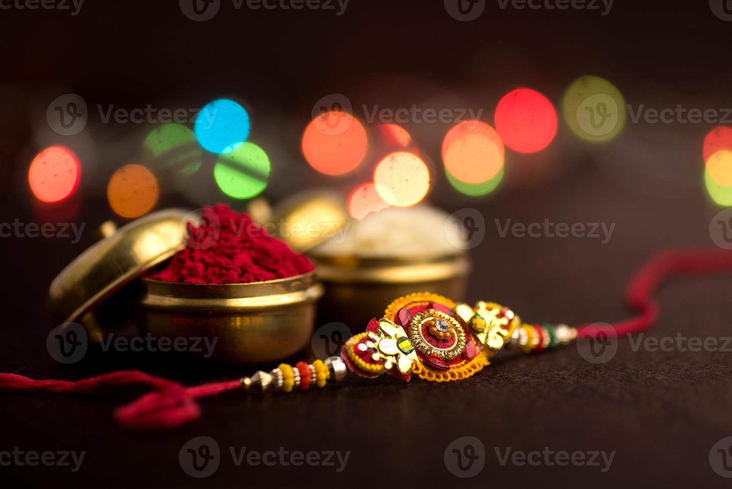 Raksha Bandhan background with an elegant Rakhi, Rice Grains and Kumkum. A traditional Indian wrist band which is a symbol of love between Brothers and Sisters. photo