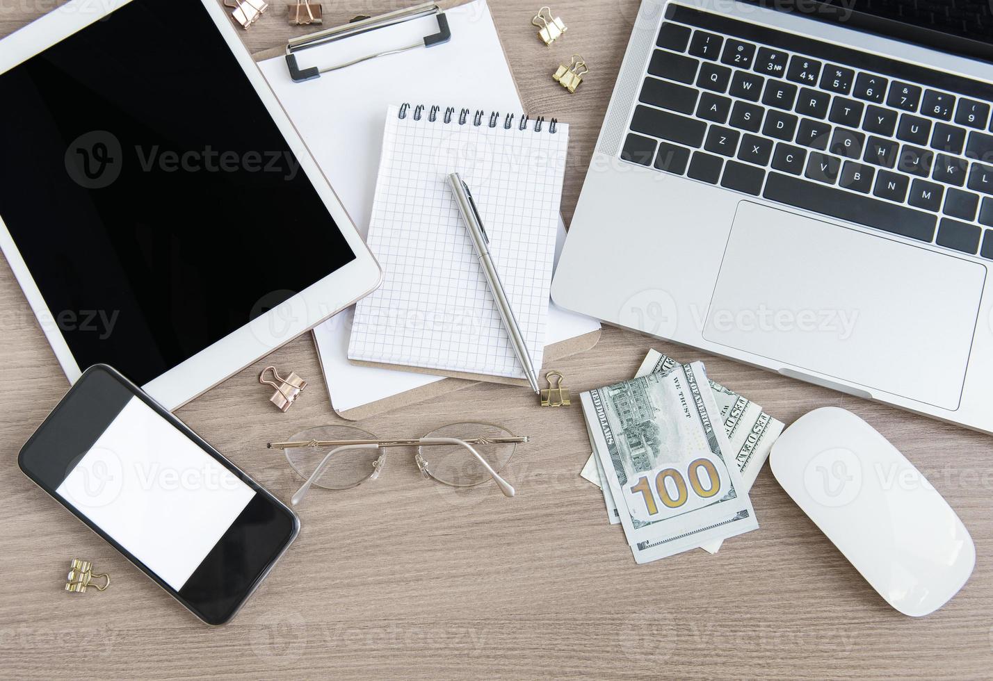 portátil con material de oficina y dinero sobre la mesa. foto