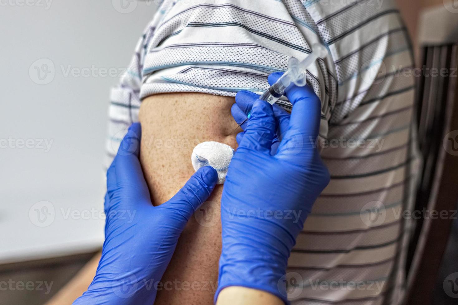 A doctor vaccinates a man against coronavirus at a clinic. Close-up. The concept of vaccination, immunization, prevention against Covid-19. photo