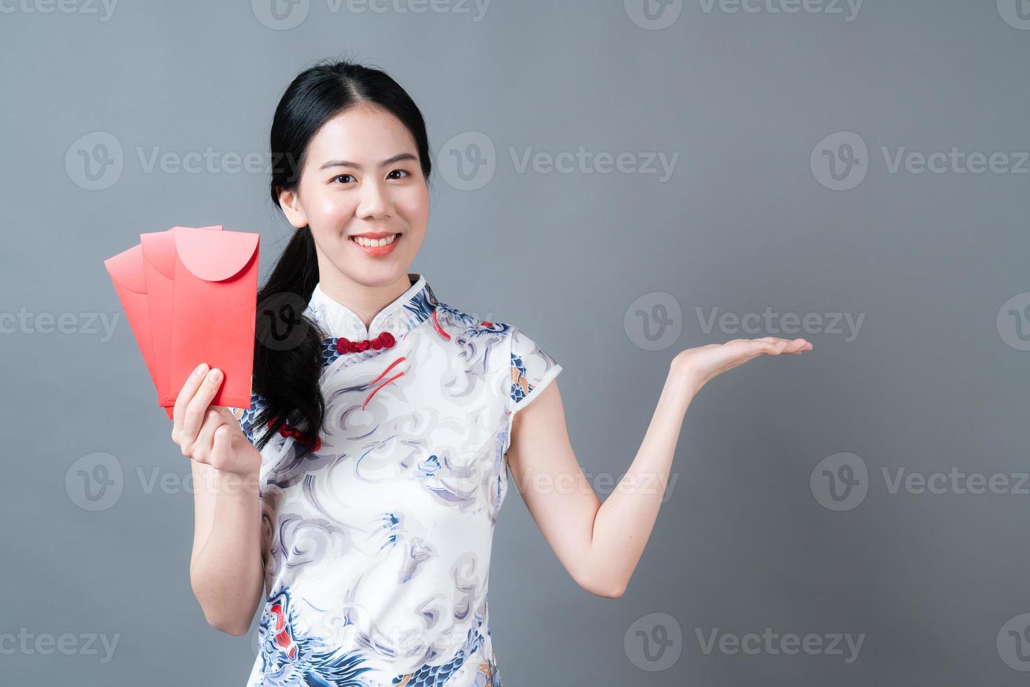 Mujer asiática vistiendo traje tradicional chino con sobre rojo o paquete rojo foto