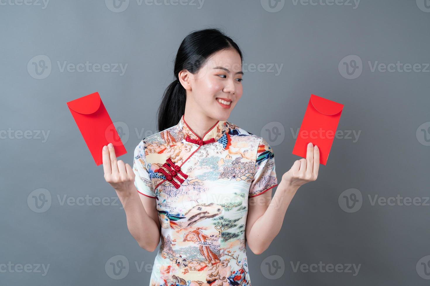 Mujer asiática vistiendo traje tradicional chino con sobre rojo o paquete rojo foto