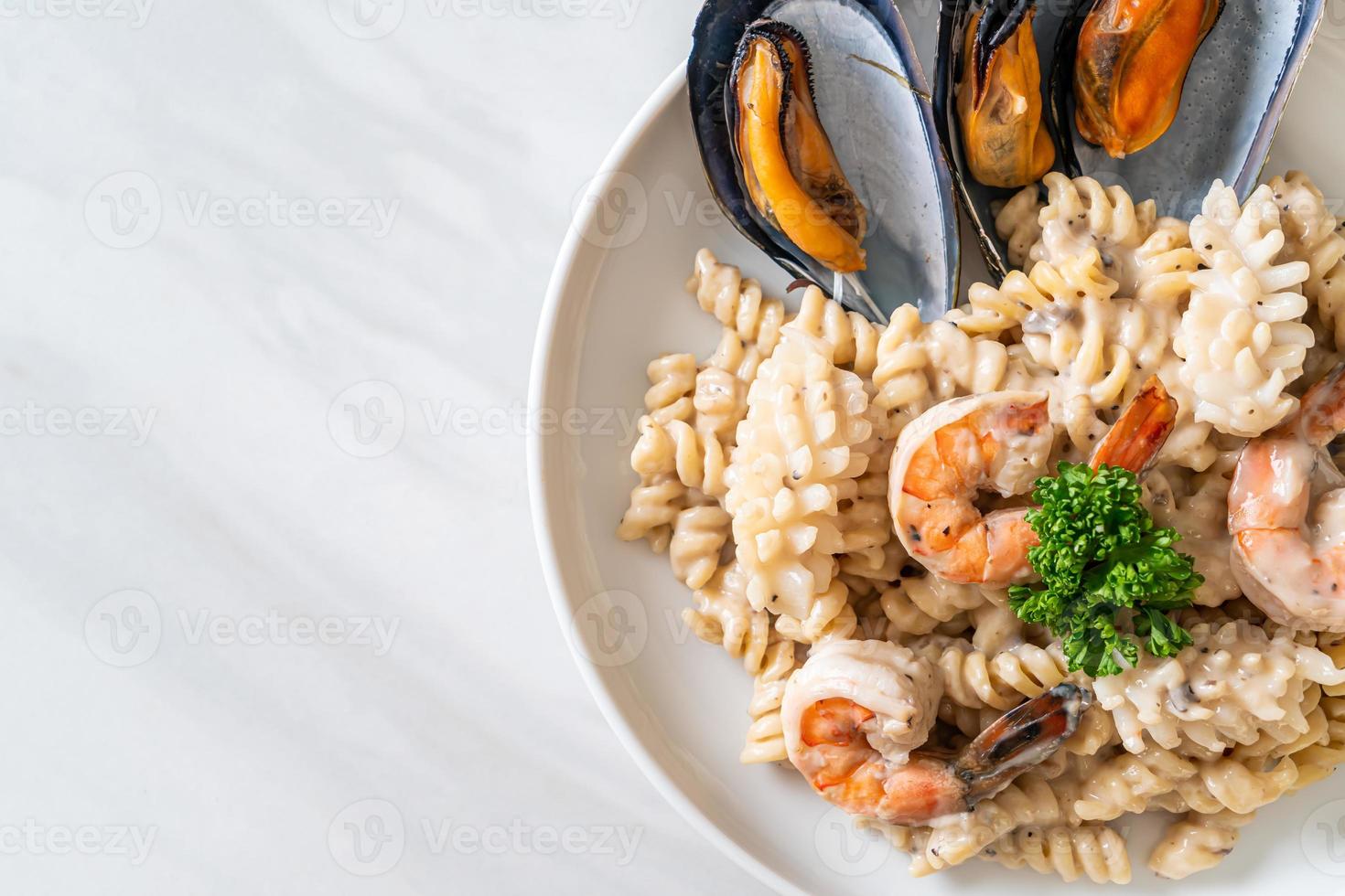 Pasta espiral con salsa de crema de champiñones y mariscos - estilo de comida italiana foto