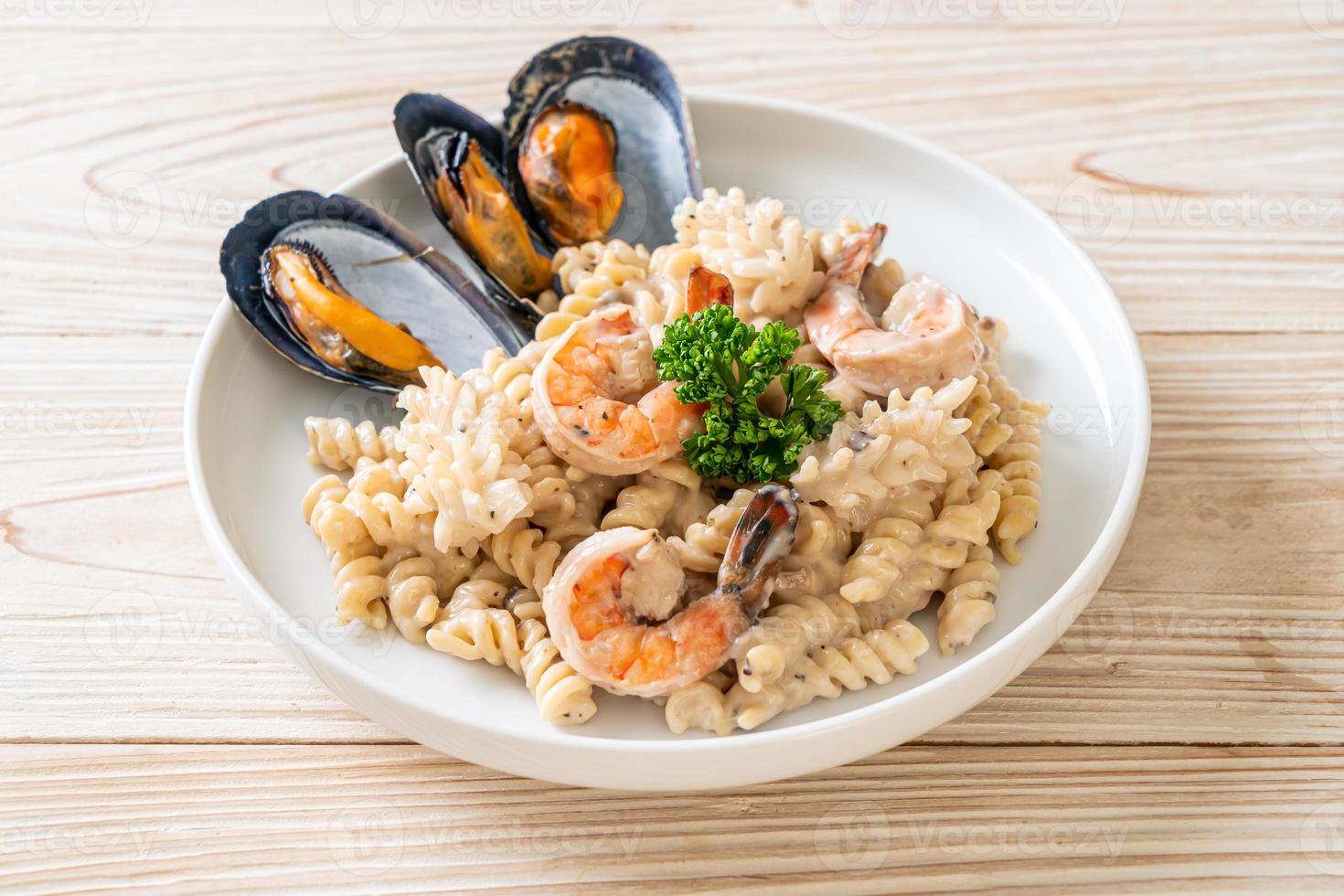 Pasta espiral con salsa de crema de champiñones y mariscos - estilo de comida italiana foto