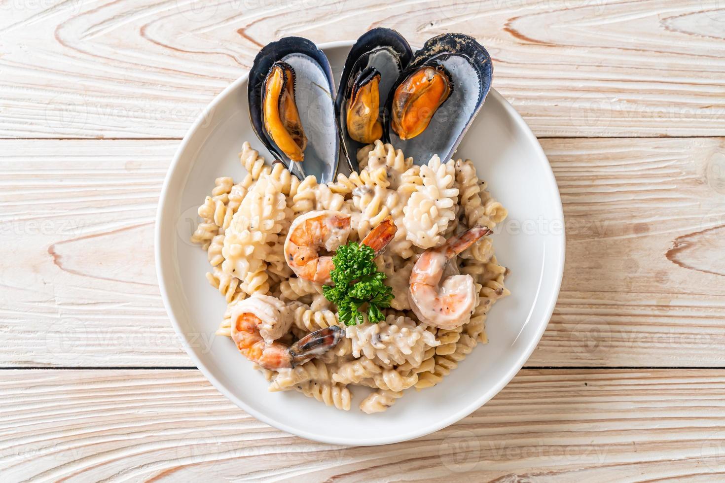 Pasta espiral con salsa de crema de champiñones y mariscos - estilo de comida italiana foto