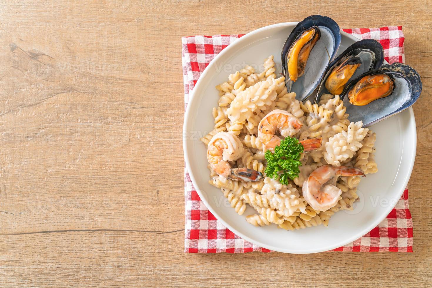 Pasta espiral con salsa de crema de champiñones y mariscos - estilo de comida italiana foto