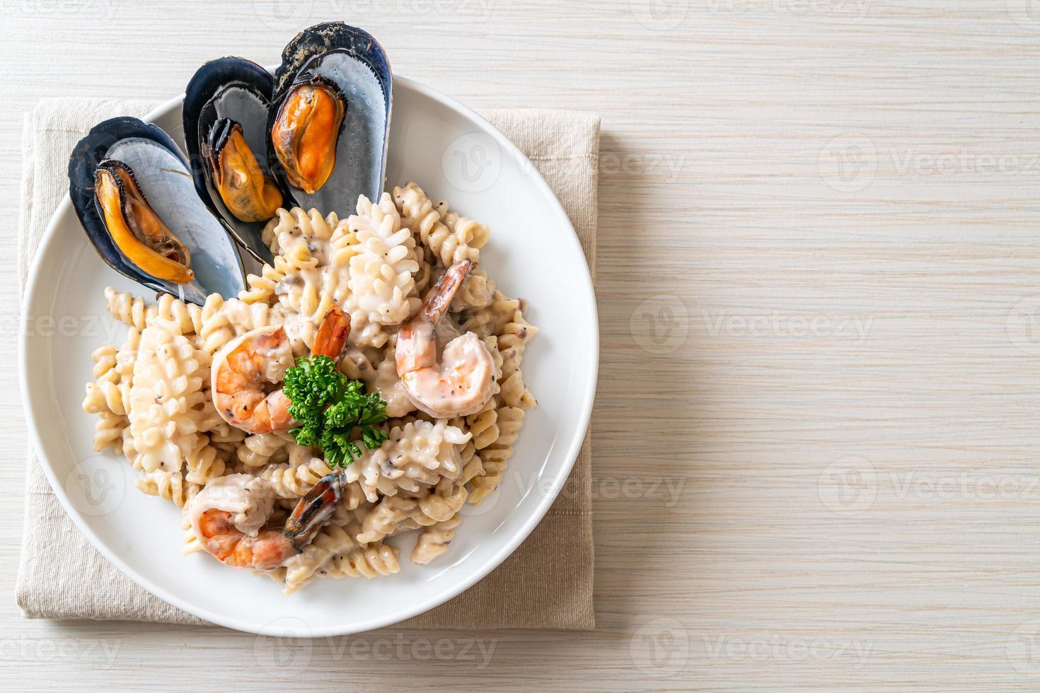 Pasta espiral con salsa de crema de champiñones y mariscos - estilo de comida italiana foto