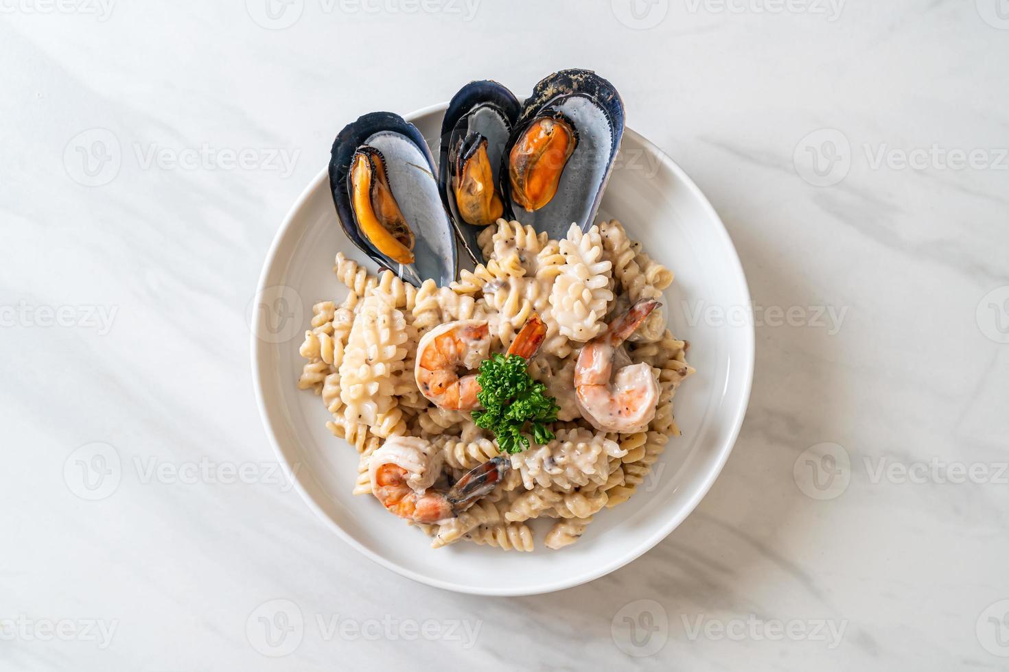 Pasta espiral con salsa de crema de champiñones y mariscos - estilo de comida italiana foto