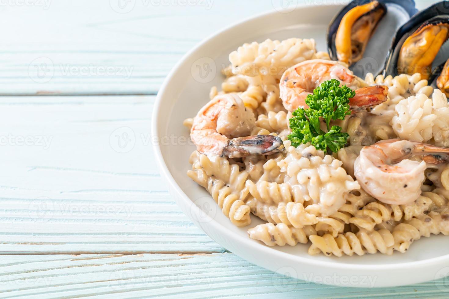 Pasta espiral con salsa de crema de champiñones y mariscos - estilo de comida italiana foto