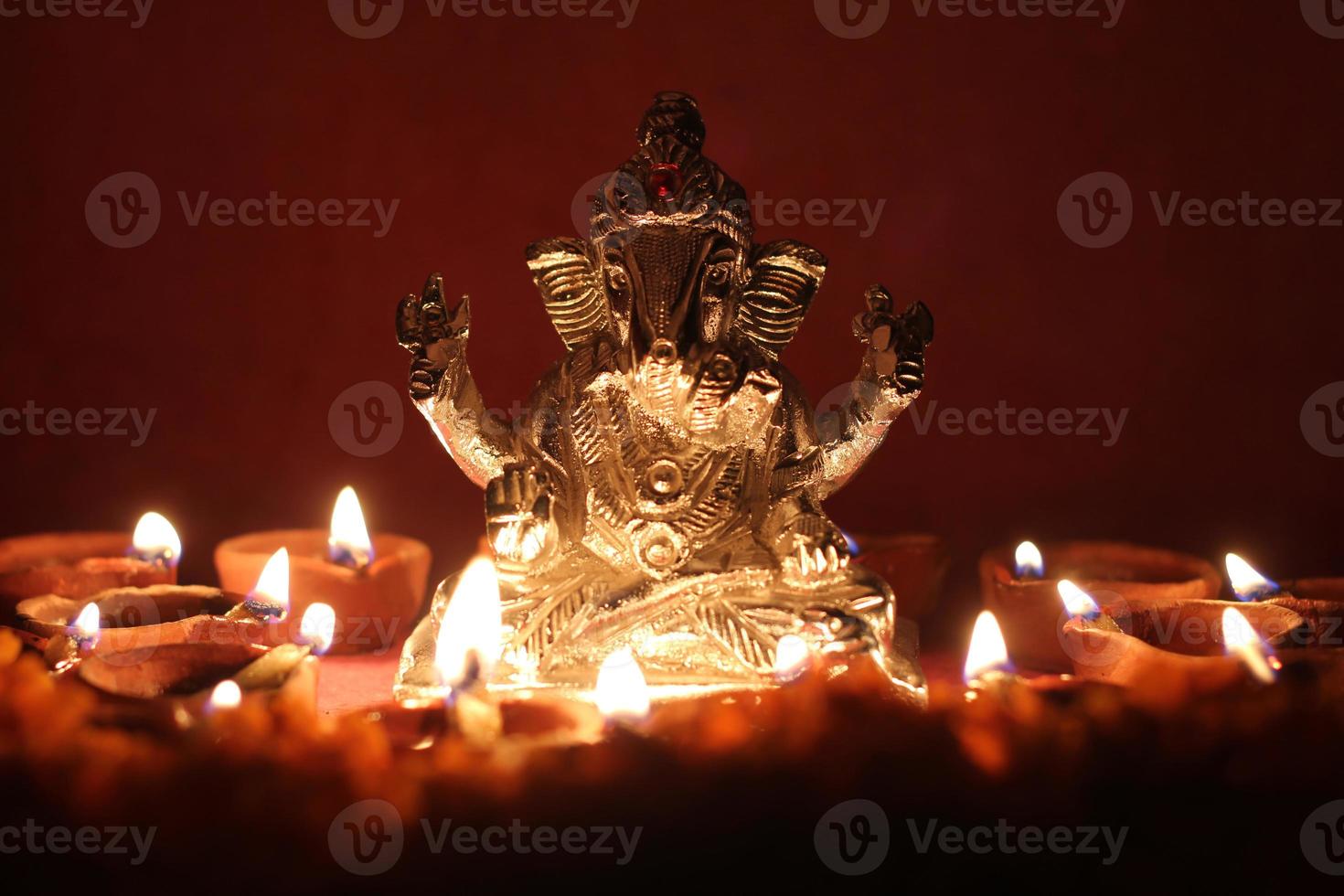 Ganesh idol surrounded with oil lamp photo