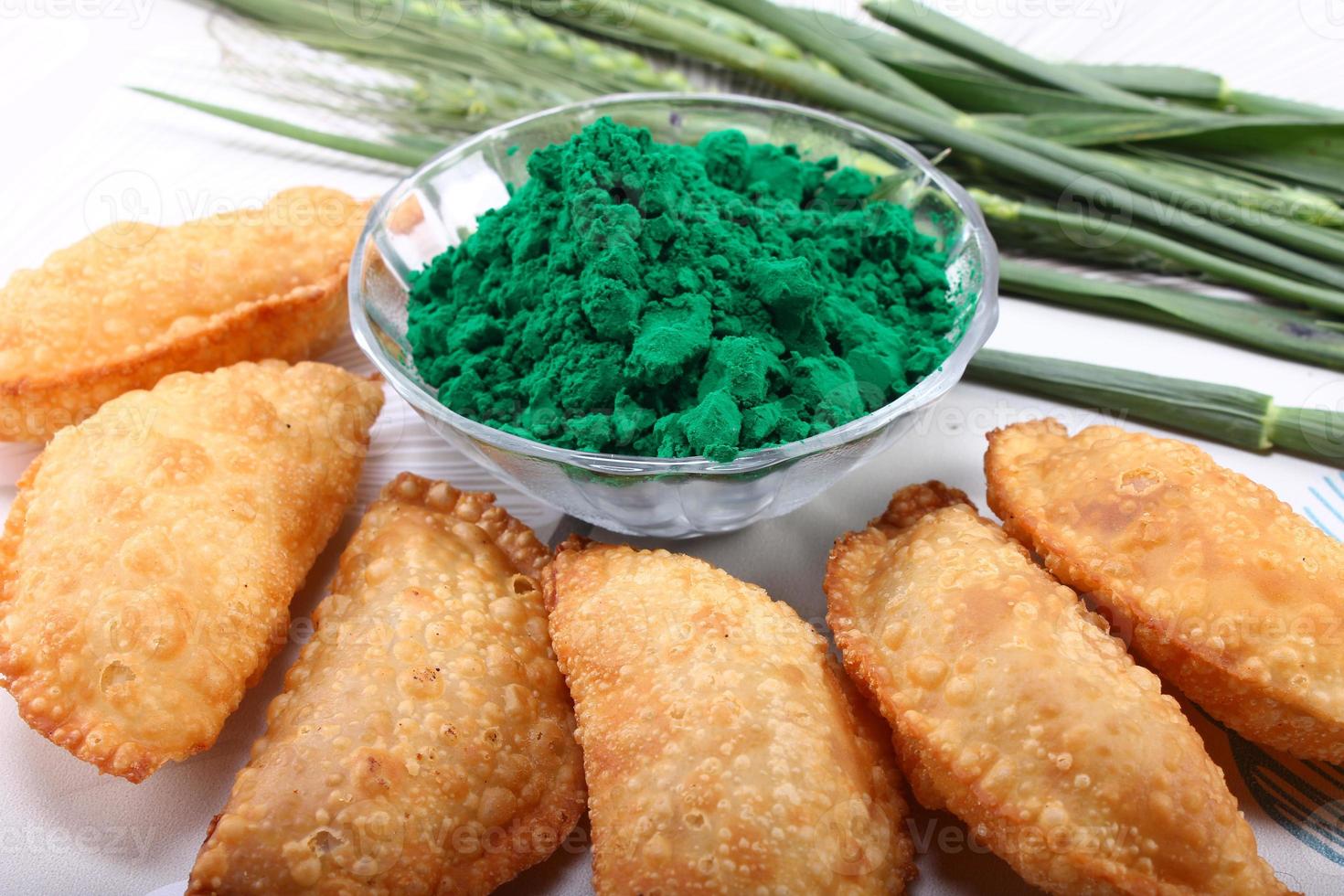 Gujia with holi green color on white background along with green onion leaves photo