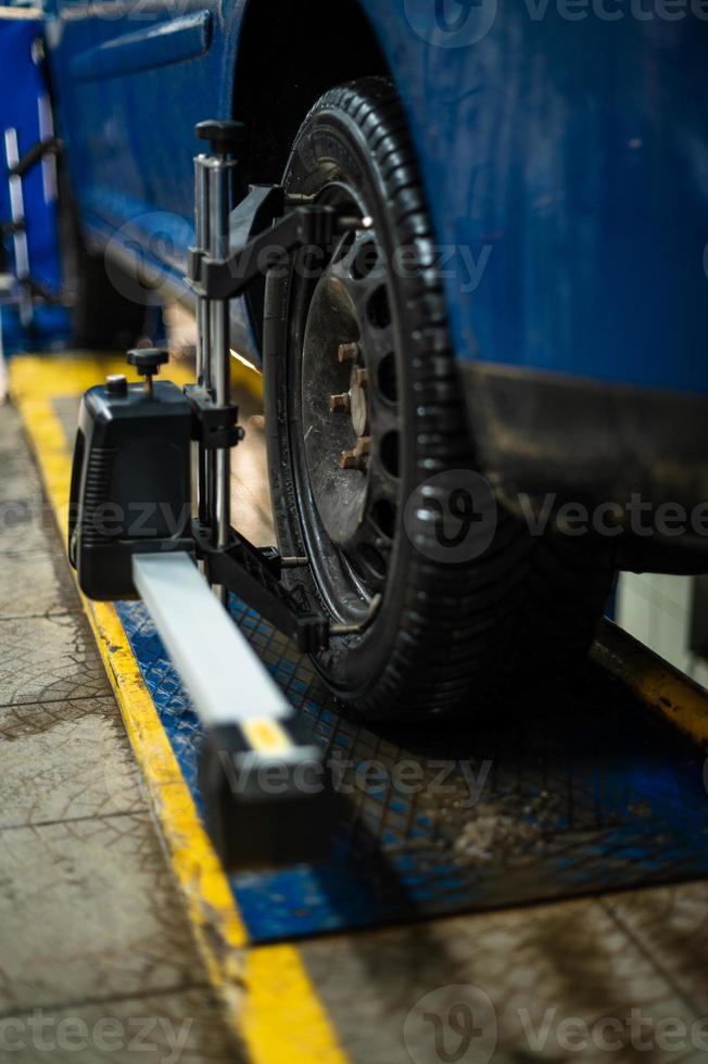 Primer plano de una llanta sujeta por un nivelador que pasa la alineación automática de las ruedas en el garaje, garaje y herramientas para el mecánico. foto