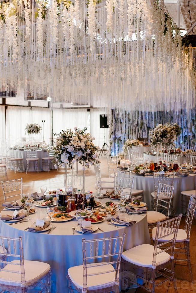 el presidium de los recién casados en el salón de banquetes del restaurante está decorado con velas y plantas verdes foto