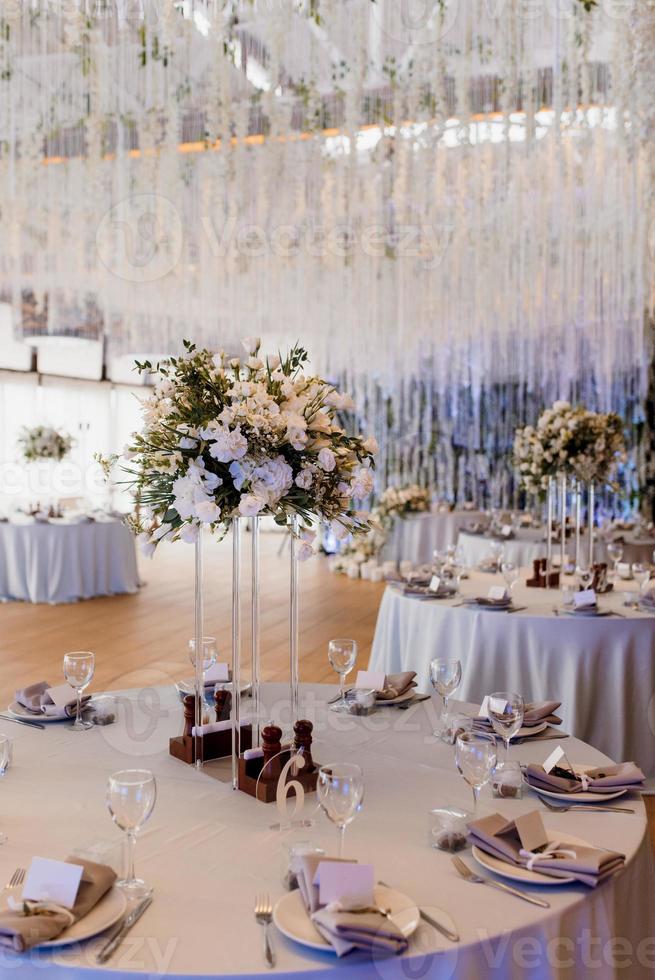 el presidium de los recién casados en el salón de banquetes del restaurante está decorado con velas y plantas verdes foto