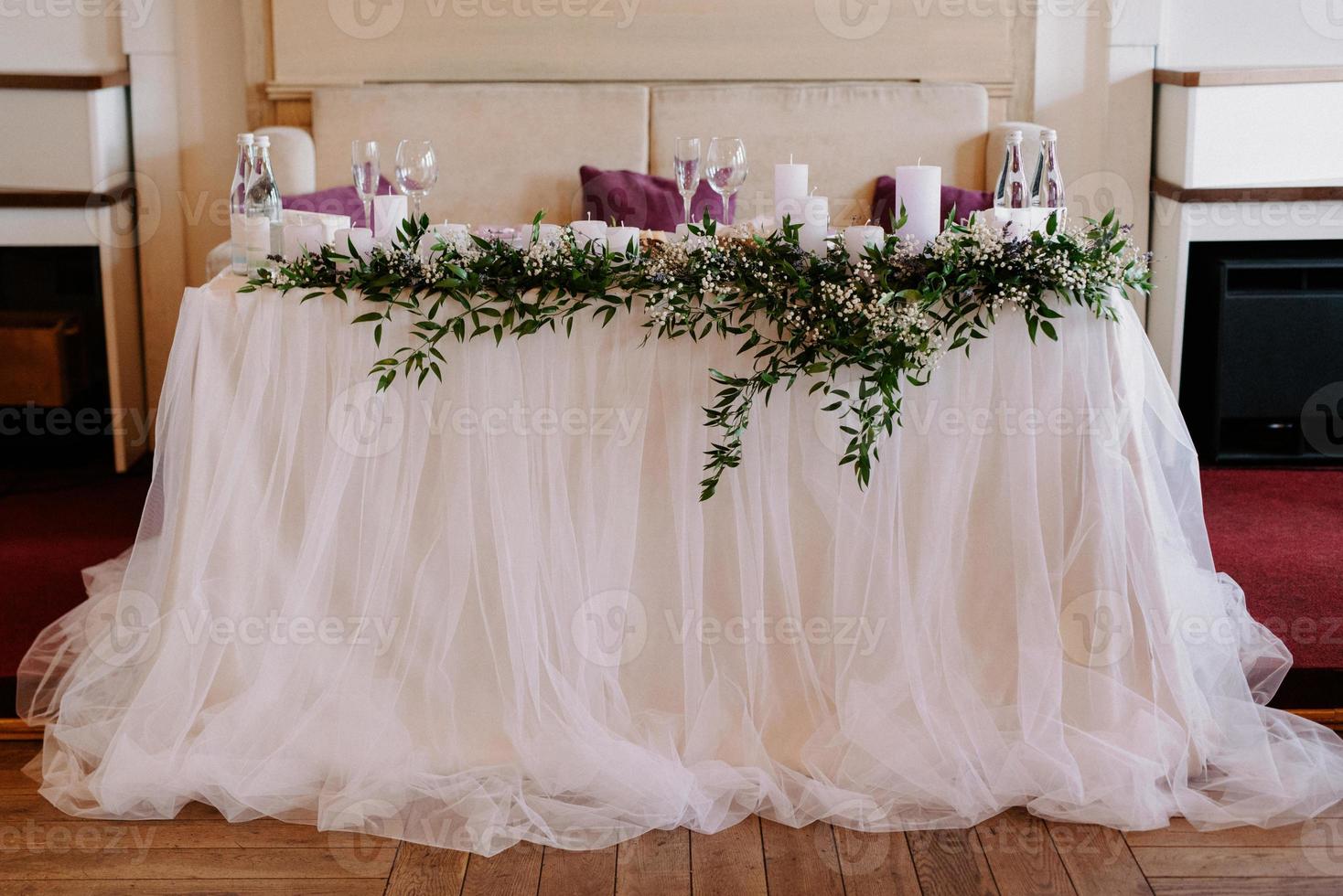 the presidium of the newlyweds in the banquet hall of the restaurant is decorated with candles and green plants photo