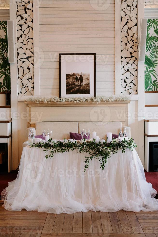 the presidium of the newlyweds in the banquet hall of the restaurant is decorated with candles and green plants photo