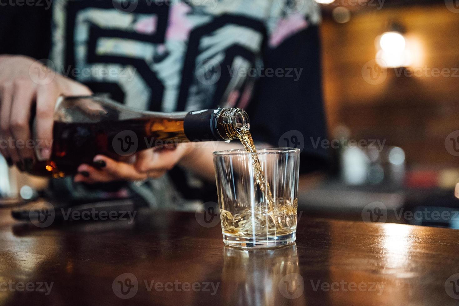 whiskey is poured into a glass from a bottle photo