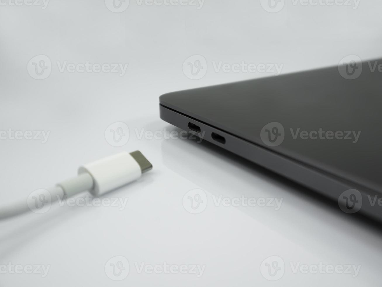 Cable tipo c y portátil sobre el fondo blanco. foto