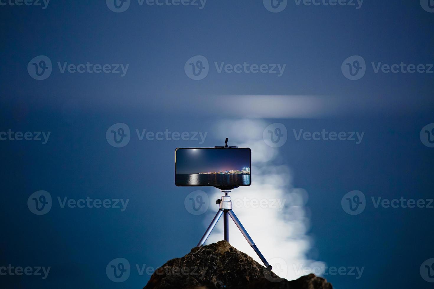 Using a smartphone on a tripod with long exposure of the sea at night photo