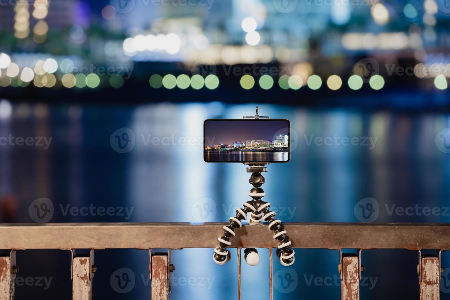 usando un teléfono inteligente en un trípode plegable con larga exposición al mar por la noche foto